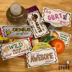 there are some candy bars on the table with an orange and water bottle next to them