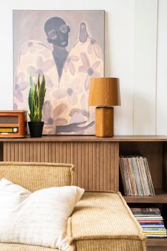 a living room with a couch, bookshelf and a painting on the wall