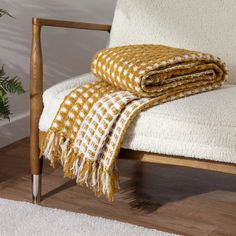 a chair with a blanket on top of it next to a potted plant