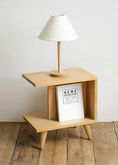 a lamp sitting on top of a wooden table next to a book shelf with an acme sign underneath it