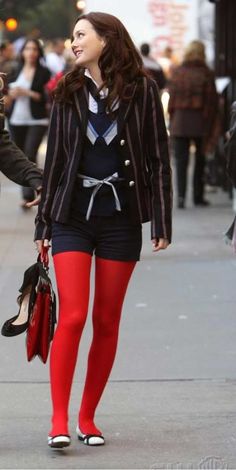 two women walking down the street talking to each other while holding hands and wearing red tights