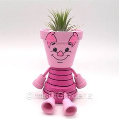 a pink potted plant with a smiling face on it's head and legs