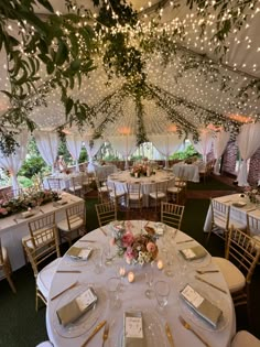 the inside of a tent with tables and chairs set up for a formal dinner or party