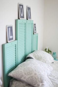 a bed with white sheets and blue shutters on the headboard is decorated with framed pictures