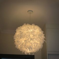 a chandelier hanging from the ceiling in a room with white cabinets and cupboards