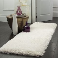 a white rug on the floor in front of a door with two vases next to it