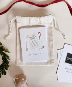 the contents of a christmas wish list laid out on a white cloth bag with red ribbon