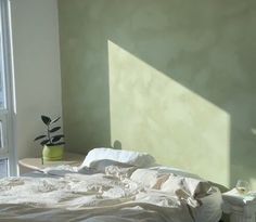 an unmade bed with white sheets and pillows next to a window in a bedroom