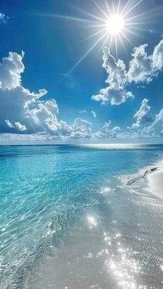 the sun shines brightly over an ocean beach with white sand and clear blue water