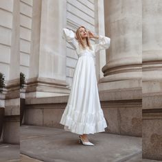 a woman in a white dress is standing on the sidewalk and looking up at something