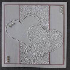 a white card with two hearts and pearls on the front, in an ornate pattern