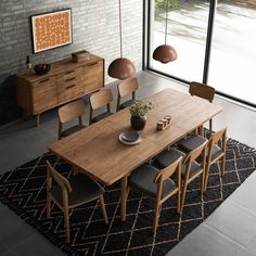 a dining room table and chairs in front of a brick wall with glass doors that look out onto the street