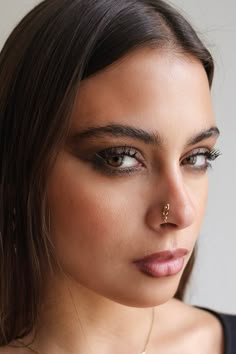 a close up of a woman wearing a necklace and nose ring with an arrow on it