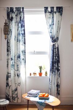 a living room with a table and curtains in front of a window filled with fruit