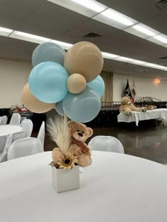 a bunch of balloons that are on top of a table in a room with white tables and chairs