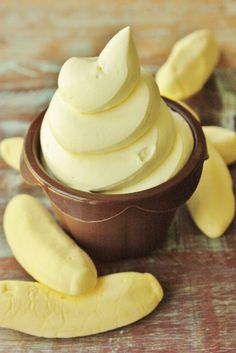 a bowl filled with whipped cream next to sliced banana peels on top of a wooden table