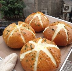 four breads with white cheese and herbs on them sitting in a cardboard box next to an oven mitt