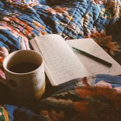 a cup of coffee and an open notebook on a bed