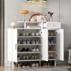 a white shoe cabinet with many pairs of shoes on it and a chandelier hanging from the ceiling