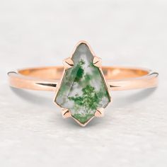 a gold ring with a green and white stone in the shape of a leaf on it