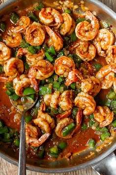 a skillet filled with shrimp, peppers and green beans on top of a wooden table