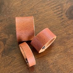 three rolls of leather tape sitting on top of a wooden table