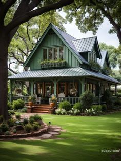 a green house with lots of windows and porches in the front yard, surrounded by trees