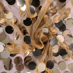 some gold and black confetti on a white table cloth with lots of circles