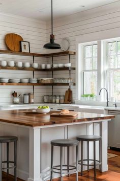 a kitchen island with two stools in front of it and shelves on the wall