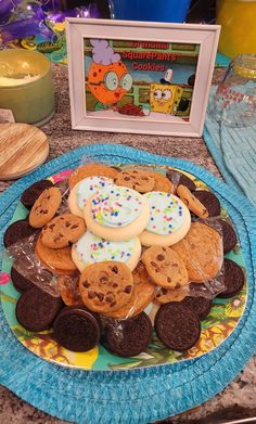 there is a plate full of cookies on the table next to a framed picture and some candles