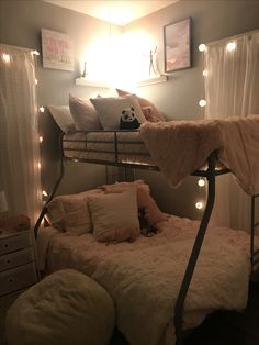 a bunk bed with lights on the ceiling and pillows in front of it, next to a night stand