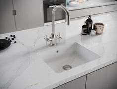 a kitchen sink sitting on top of a white counter