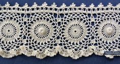 crocheted lace with white flowers on blue background, closeup photo taken from the bottom