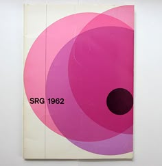 a book with pink and purple circles on the cover, in front of a white wall