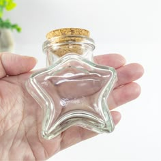 a hand holding a glass bottle with a star shaped cork in the top and bottom