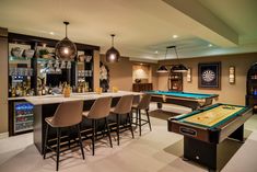 a game room with pool table, bar and stools