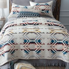 a bed covered in a white and blue quilt next to a lamp on a nightstand