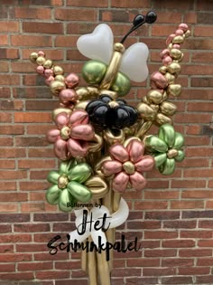 a vase filled with lots of flowers on top of a wooden table next to a brick wall