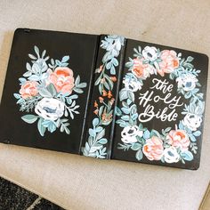 two black notebooks with floral designs on them sitting on a chair next to a pillow