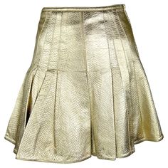 This metallic gold leather flare skirt, designed by Gianni Versace for his Fall/Winter 1994 collection, is a striking example of his bold, glamorous aesthetic. The lavender version of this reptile-embossed skirt was modeled by Kate Moss as part of runway look 59 and also featured in the season's ad campaign with Christy Turlington, photographed by Richard Avedon. Crafted from embossed leather, this high-waisted skirt boasts a pleated flare hem that adds movement and drama. Recently worn by Margo