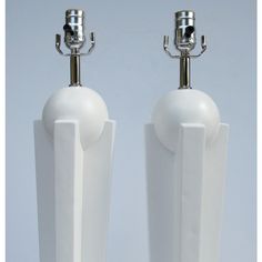 two white vases with metal handles on top of each other, one holding a light bulb