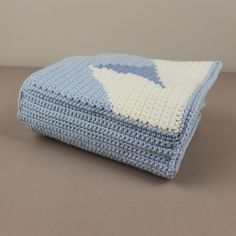 a blue and white crocheted blanket sitting on top of a brown table next to a gray wall