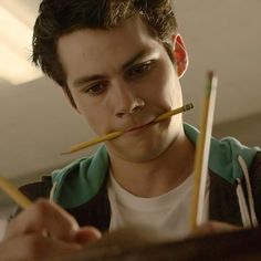 a young man holding two pencils in his mouth