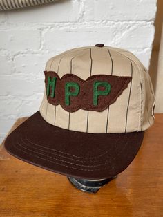 This is a vintage made is USA trucker style hat that I added vintage patches to! Wool 'MPP' patch from the 1940s, and an embroidered 'Mike' workwear name patch. One of a kind. Brown and tan with stripes. In deadstock condition. Adjustable snapback, one size fits most. Gender neutral. All sales are final, so please refer to photos and description. Retro Trucker Hat With Logo Patch, Retro Brown Cotton Baseball Cap, Vintage Brown Cotton Baseball Cap, Vintage 5-panel Trucker Hat With Logo Patch, Retro Trucker Hat With Embroidered Logo, Vintage Cotton 5-panel Snapback Hat, Vintage Flat Bill Baseball Cap, Vintage Cotton Hat With Flat Bill, Vintage Cotton Flat Bill Hats