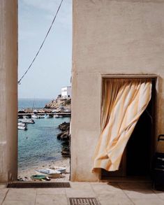 an open door leading to a beach with boats in the water