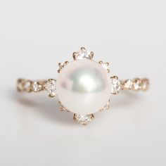 a pearl and diamond ring on a white surface