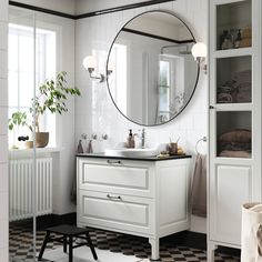 a bathroom with black and white checkered flooring, a round mirror above the sink