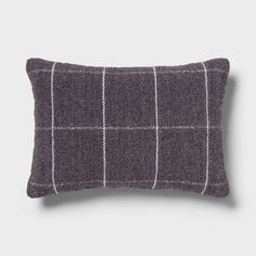 a gray and white plaid pillow on a grey background