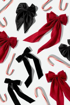 several bows and candy canes on a white surface with red and black ribbons around them