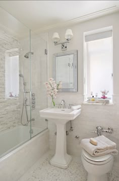 a white bathroom with a toilet, sink and shower